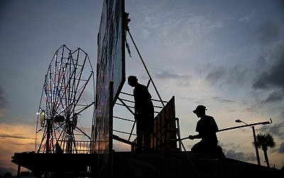 Workers dismantle the facade of a funhouse at an amusement park ahead of Hurricane Irma in Daytona Beach, Fla., Thursday, Sept. 7, 2017. (AP Photo/David Goldman)
