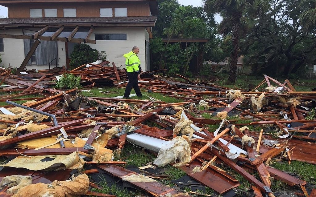 Palm Bay officer Dustin Terkoski walks over debris from a two-story home at Palm Point Subdivision in Brevard County, Florida, after a tornado touched down on Sunday, Sept. 10, 2017 as Hurricane Irma passed over the state. (Red Huber/Orlando Sentinel via AP)