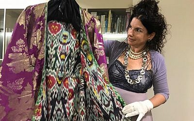 Efrat Assaf-Shapira shows off a Bukharan women’s coat from the Jewish clothing collection at the Israel Museum in Jerusalem, September 27, 2017. (Andrew Tobin)