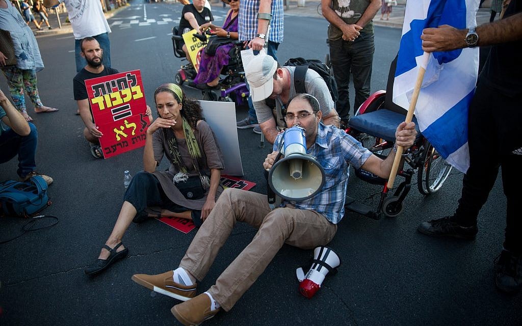 Disabled activists block Ibn Gvirol street in Tel Aviv as part of a protest calling for an increase in government stipends, August 31, 2017. (Miriam Alster/Flash90)