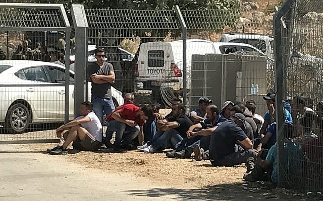Palestinian laborers sit outside the Har Adar settlement after they were removed from the area by soldiers following a deadly terror attack at the entrance to the community on September 26, 2017. (Jacob Magid/Times of Israel)