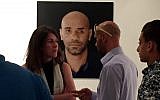 Luai Abed (right) stands in front of a portrait photograph of himself at an exhibition of works by photo journalist Tali Mayer, who, herself, was wounded by a black sponge bullet in 2014 while covering a demonstration. (Ido Grumer)