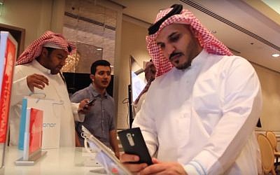 Saudi men trying out smartphones at a conference. (YouTube screenshot)