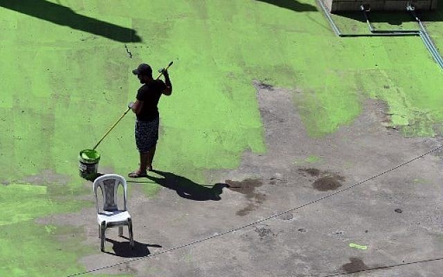 Lebanese painters take part in a project that aims to draw the word Peace in Arabic across 85 rooftops, in Tripoli's Syria street which separates the Sunni neighborhood of Bab al-Tabbaneh from the Alawite neighborhood of Jabal Mohsen, in Tripoli on September 28, 2017. (AFP / Joseph EID)