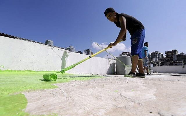 Lebanese painters take part in a project that aims to draw the word Peace in Arabic across 85 rooftops, in Tripoli's Syria street which separates the Sunni neighborhood of Bab al-Tabbaneh from the Alawite neighborhood of Jabal Mohsen, in Tripoli on September 28, 2017. (AFP / Joseph EID)