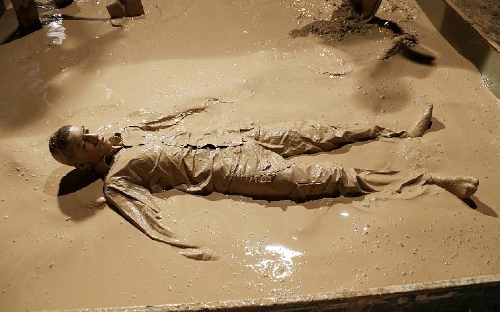 An Iranian Shiite Muslim rolls over in a mud pond during the 'Kharrah Mali' (Mud Rubbing) ritual to mark the Ashura religious ceremony in the city of Khorramabad, some 470 kms southwest of Tehran, early in the morning on October 1, 2017. (Atta Kenare/AFP)