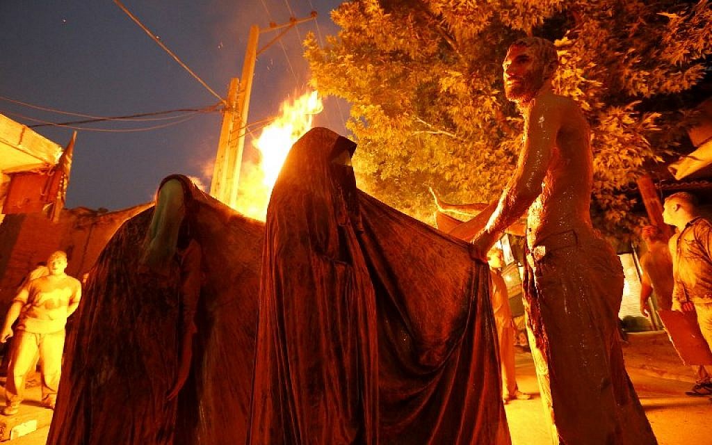 Iranian Shiite Muslim women gather around a bonfire after rubbing mud on their body during the 'Kharrah Mali' (Mud Rubbing) ritual to mark the Ashura religious ceremony in the city of Khorramabad, some 470 kms southwest of Tehran, early in the morning on October 1, 2017. (Atta Kenare/AFP)