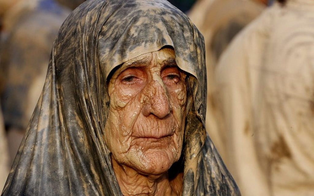 An Iranian Shiite Muslim woman looks on after rubbing mud on her body during the 'Kharrah Mali' (Mud Rubbing) ritual to mark the Ashura religious ceremony in the city of Khorramabad, some 470 kms southwest of Tehran, early in the morning on October 1, 2017. (Atta Kenare/AFP)