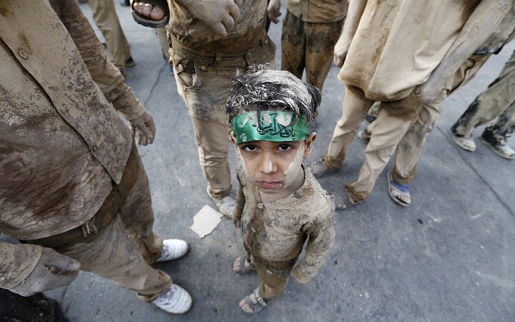 A boy sits amid Iranian Shiite Muslims beating their chests as they take part in the 'Kharrah Mali' (Rubbing Mud) ritual during the Ashura religious ceremony in the city of Khorramabad, 470 kms southwest of Tehran, on October 01, 2017. (Atta Kenare/AFP)