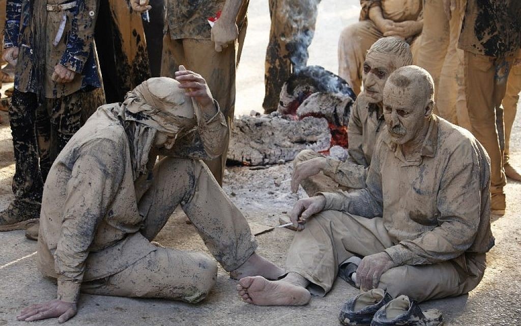 Iranian Shiite Muslims sit after rubbing mud on their body during the 'Kharrah Mali' (Mud Rubbing) ritual to mark the Ashura religious ceremony in the city of Khorramabad, some 470 kms southwest of Tehran, early in the morning on October 1, 2017. (Atta Kenare/AFP)