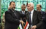 Fatah's Azzam al-Ahmad, right, and Saleh al-Arouri of Hamas shake hands after signing a reconciliation deal in Cairo, on October 12, 2017, as the two rival Palestinian movements ended their decade-long split following negotiations overseen by Egypt. (AFP/Khaled Desouki)