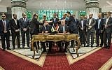 Hamas's new deputy leader Salah al-Arouri (seated, left) and Fatah's Azzam al-Ahmad (seated, right) sign a reconciliation deal in Cairo on October 12, 2017, as the two rival Palestinian movements work to end their decade-long split following negotiations overseen by Egypt. (AFP/Khaled Desouki)