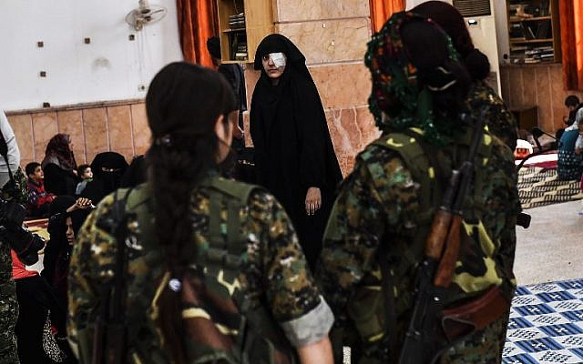 A Syrian woman looks at fighters from the Syrian Democratic Forces as civilians gather on the western front after fleeing the centre of Raqa on October 12, 2017. (Bulent Kilic/AFP) A Syrian woman looks at fighters from the Syrian Democratic Forces as civilians gather on the western front after fleeing the centre of Raqa on October 12, 2017. (Bulent Kilic/AFP)