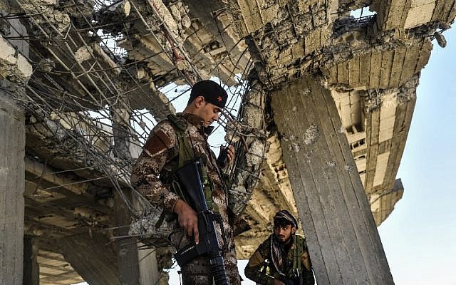 Illustrative: Members of the Syrian Democratic Forces (SDF), backed by US special forces, walk on a building near Raqa's central hospital as they clear the last positions on the frontline on October 16, 2017 in the Islamic State (IS) group jihadists crumbling stronghold.(Bulent Kilic/AFP) Illustrative: Members of the Syrian Democratic Forces (SDF), backed by US special forces, walk on a building near Raqa's central hospital as they clear the last positions on the frontline on October 16, 2017 in the Islamic State (IS) group jihadists crumbling stronghold.(Bulent Kilic/AFP)