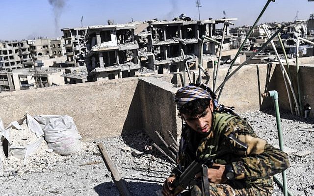 Illustrative: Members of the Syrian Democratic Forces (SDF), backed by US special forces, walk on a building near Raqa's central hospital as they clear the last positions on the frontline on October 16, 2017 in the Islamic State (IS) group jihadists crumbling stronghold. (Bulent Kilic/AFP) Illustrative: Members of the Syrian Democratic Forces (SDF), backed by US special forces, walk on a building near Raqa's central hospital as they clear the last positions on the frontline on October 16, 2017 in the Islamic State (IS) group jihadists crumbling stronghold. (Bulent Kilic/AFP)