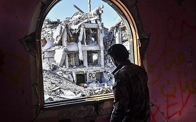 A member of the Syrian Democratic Forces (SDF), backed by US special forces, looks out from a building at the front line in Raqqa on October 16, 2017 in the Islamic State (IS) jihadist group's crumbling stronghold. (AFP PHOTO/BULENT KILIC)
