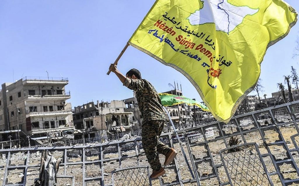 A member of the Syrian Democratic Forces (SDF), backed by US special forces, holds up his group's flag at the iconic Al-Naim square in Raqqa on October 17, 2017. (AFP PHOTO / BULENT KILIC)