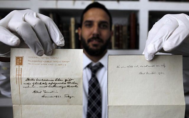 A picture taken on October 19, 2017, shows Gal Wiener, owner and manager of the Winner's auction house in Jerusalem, displaying two notes written by Albert Einstein, in 1922, on hotel stationary from the Imperial Hotel in Tokyo Japan. A note that Albert Einstein gave to a courier in Tokyo, briefly describing his theory on happy living, has surfaced after 95 years and is up for auction in Jerusalem. (AFP PHOTO / MENAHEM KAHANA)