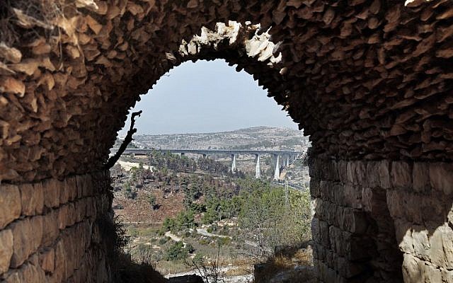 A picture taken from inside an old house in Palestinian village of Lifta which was abandoned during fighting in the 1948 Arab-Israeli war, shows the bridge for a new train line on the outskirts of Jerusalem, on October 20, 2017. (AFP PHOTO / THOMAS COEX) A picture taken from inside an old house in Palestinian village of Lifta which was abandoned during fighting in the 1948 Arab-Israeli war, shows the bridge for a new train line on the outskirts of Jerusalem, on October 20, 2017. (AFP PHOTO / THOMAS COEX)