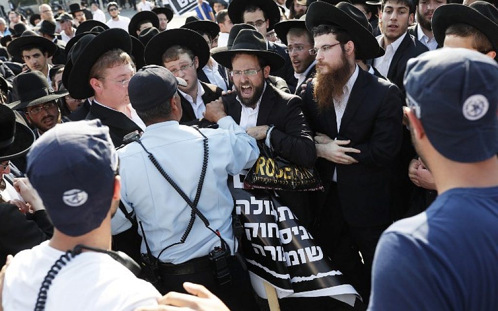 Police officers stand guard as ultra-Orthodox protesters demonstrate against the draft outside the Knesset in Jerusalem on October 23, 2017.  (Thomas Coex/AFP)