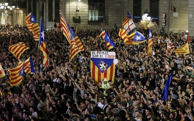 A flag with the text in Catalan "The people lead" is held up as people gather to celebrate the proclamation of a Catalan republic at the Sant Jaume square in Barcelona, on October 27, 2017. (AFP/Pau Barrena) A flag with the text in Catalan "The people lead" is held up as people gather to celebrate the proclamation of a Catalan republic at the Sant Jaume square in Barcelona, on October 27, 2017. (AFP/Pau Barrena)