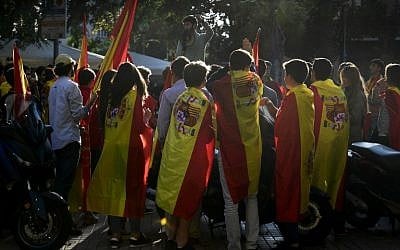 A young man uses a megaphone as other youths wrapped in Spanish flags listen to him  during a demonstration calling for unity in Barcelona on October 28, 2017, a day after direct control was imposed on Catalonia over a bid to break away from Spain.(AFP/PIERRE-PHILIPPE MARCOU)