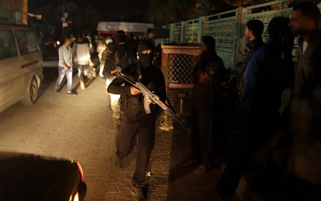 Masked Palestinian men holding rifles walk outside the al-Aqsa hospital's morgue in Deir el-Balah in the central Gaza Strip as six Palestinians were killed after Israel blew up what it said was a tunnel stretching from Gaza into its territory, on October 30, 2017. (AFP PHOTO/MAHMUD HAMS)