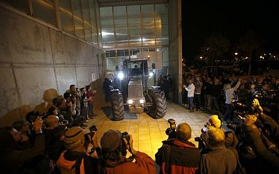 As journalists take pictures, a parked tractor blocks the door of a sports center, assigned to be a polling station by the Catalan government and where Catalan President Carles Puigdemont is expected to vote, in Sant Julia de Ramis, near Girona, Spain, October 1, 2017. (AP Photo/Francisco Seco)