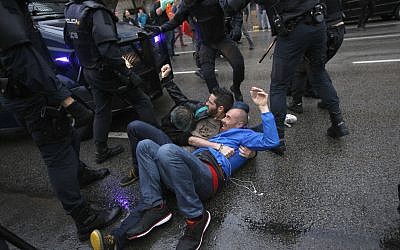 Three man hold to each other as they try to block a Spanish police van from approaching a voting site to prevent would-be voters from voting at a school assigned to be a polling station by the Catalan government in Barcelona, Spain, 1 October 2017. (AP Photo/Emilio Morenatti)