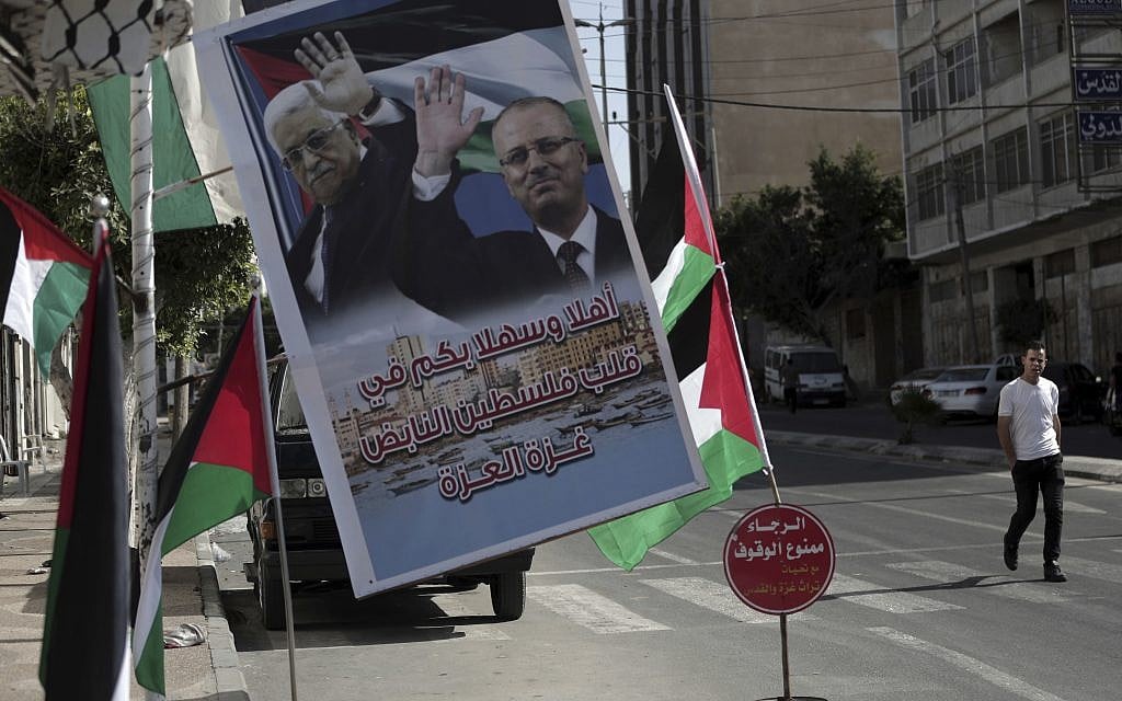 A poster of Palestinian Authority President Mahmoud Abbas and PA Prime Minister Rami Hamdallah hangs on a street in Gaza City, October 1, 2017 (AP Photo/Khalil Hamra)