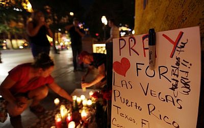 People pause at a memorial on October 3, 2017, set up for victims of the mass shooting in Las Vegas two days before in which 59 were killed and hundreds wounded.  (AP Photo/Gregory Bull)