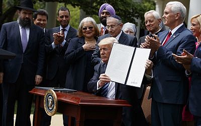 In this May 4, 2017 file photo, President Donald Trump holds up a signed executive order aimed at easing an IRS rule limiting political activity for churches in the Rose Garden of the White House in Washington.    (AP Photo/Evan Vucci)