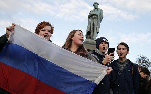 Demonstrators sing as they hold the Russian flag during a rally in Moscow, Russia, Saturday, Oct. 7, 2017. Opposition leader Alexei Navalny has worked to organize protests in support of his presidential bid across Russia on Saturday, President Vladimir Putin's birthday. (AP Photo/Alexander Zemlianichenko)