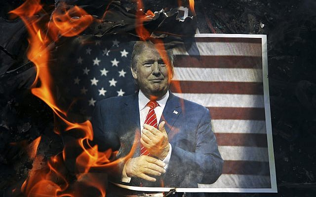 In this Wednesday, Sept. 27, 2017 file photo, a portrait of US President Donald Trump is set on fire by Iranian mourners during the state funeral of Mohsen Hojaji, a young Revolutionary Guard soldier beheaded by the Islamic State group in Syria, in Tehran, Iran. (AP/Ebrahim Noroozi)
