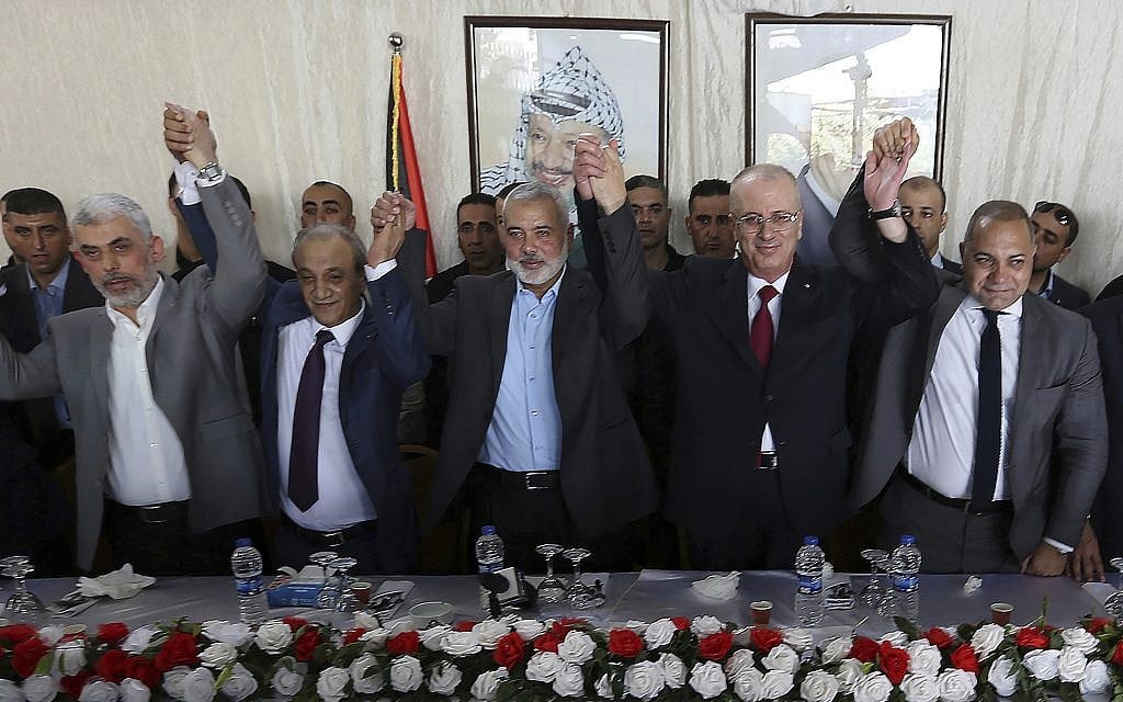 From left in front row, Hamas leader in the Gaza Strip Yahya Sinwar, Head of Palestinian General Intelligence Majid Faraj, Head of the Hamas political bureau Ismail Haniyeh, PA Prime Minister Rami Hamdallah and an Egyptian mediator hold their hands up during a meeting in Gaza City, October 2, 2017. (AP Photo/Prime Minister Office, File)