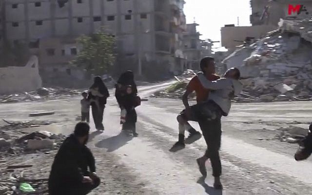 This frame grab from a video provided on Friday, Oct. 13, 2017 by Turkey-based Kurdish Mezopotamya agency media outlet shows Syrian civilians run on a damaged street as they fleeing from the areas that still controlled by the Islamic State militants, in Raqqa, Syria. Scores of civilians including women and children are fleeing the last few remaining neighborhoods held by the Islamic State group in Syria's northern city of Raqqa, ahead of an anticipated final push by US-backed fighters seeking to liberate the city. (Mezopotamya Agency, via AP) This frame grab from a video provided on Friday, Oct. 13, 2017 by Turkey-based Kurdish Mezopotamya agency media outlet shows Syrian civilians run on a damaged street as they fleeing from the areas that still controlled by the Islamic State militants, in Raqqa, Syria. Scores of civilians including women and children are fleeing the last few remaining neighborhoods held by the Islamic State group in Syria's northern city of Raqqa, ahead of an anticipated final push by US-backed fighters seeking to liberate the city. (Mezopotamya Agency, via AP)