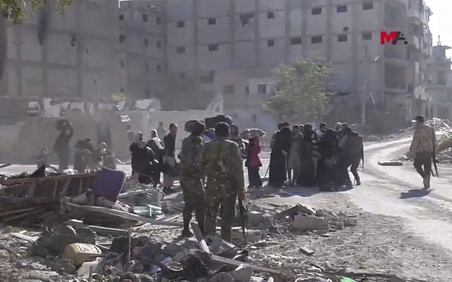 This frame grab from a video provided on Friday, Oct. 13, 2017 by Turkey-based Kurdish Mezopotamya agency media outlet that is consistent with independent AP reporting, shows US-backed Syrian Democratic Forces (SDF) fighters, stand around Syrian civilians who fled from the areas that still controlled by the Islamic State militants, in Raqqa, Syria. (Mezopotamya Agency, via AP) This frame grab from a video provided on Friday, Oct. 13, 2017 by Turkey-based Kurdish Mezopotamya agency media outlet that is consistent with independent AP reporting, shows US-backed Syrian Democratic Forces (SDF) fighters, stand around Syrian civilians who fled from the areas that still controlled by the Islamic State militants, in Raqqa, Syria. (Mezopotamya Agency, via AP)