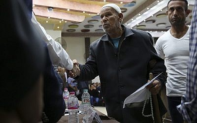 In this Tuesday, Oct. 17, 2017 photo, Abulrahem Abdrabo, whose son was killed during the internal fighting between Hamas and Fatah-led Palestinian Authority in 2007, shakes hands as he receives a cheque for $50,000 during a social reconciliation ceremony in Beit Lahiya City, Gaza Strip. (AP Photo/Adel Hana)