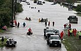 Houston residents making their way out of a flooded neighborhood after it was inundated with rainwater following Hurricane Harvey, Aug. 29, 2017. (Scott Olson/Getty Images via JTA)