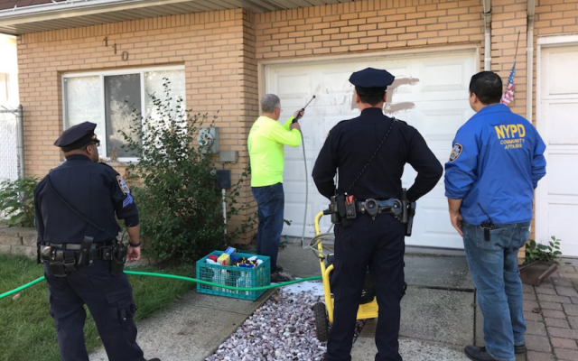 New York police crew members removing a swastika from a garage in Staten Island. (NYPD 23rd Precinct via JTA)