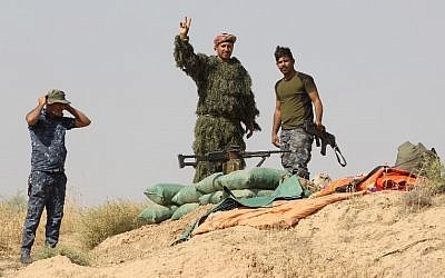 Iraqi forces gesture from a river bank across from Kurdish peshmerga positions on October 14, 2017, on the southern outskirts of Kirkuk. (AFP PHOTO / AHMAD AL-RUBAYE)