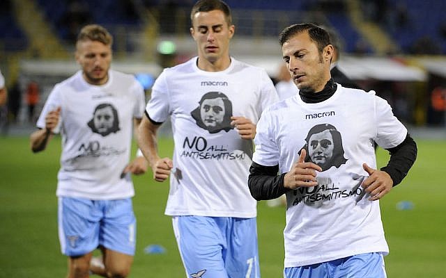 Lazio players wear a shirt depicting Anne Frank saying "No to anti-Semitism," in response to anti-Semitic stickers left by their fans at a previous match, during the Serie A match between Bologna FC and SS Lazio at Stadio Renato Dall'Ara in Bologna, Italy, on October 25, 2017. (Marco Rosi/Getty Images via JTA) Lazio players wear a shirt depicting Anne Frank saying "No to anti-Semitism," in response to anti-Semitic stickers left by their fans at a previous match, during the Serie A match between Bologna FC and SS Lazio at Stadio Renato Dall'Ara in Bologna, Italy, on October 25, 2017. (Marco Rosi/Getty Images via JTA)