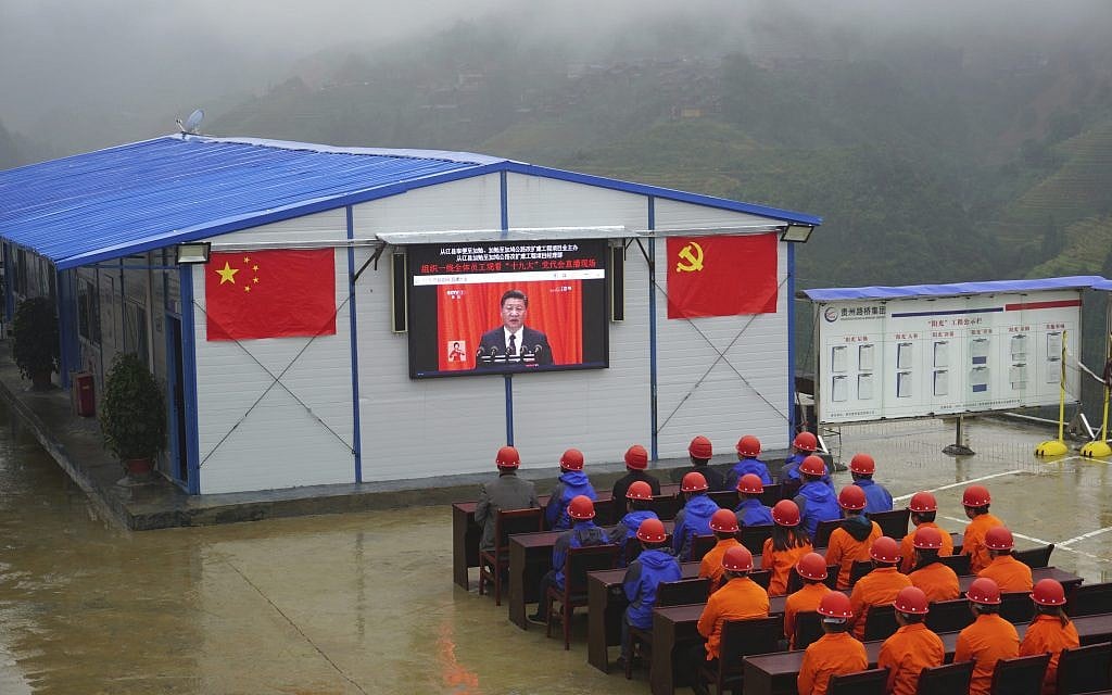 Road construction workers watch a screen showing a speech by Chinese President Xi Jinping during the opening ceremony of the 19th Party Congress in Congjiang county in southwestern China's Guizhou province Wednesday, Oct. 18, 2017. (Chinatopix via AP)