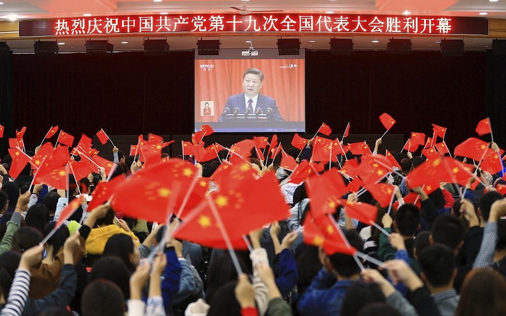 Students wave flags as they watch a speech by Chinese President Xi Jinping during the opening ceremony of China's 19th Party Congress in Huaibei in eastern China's Anhui province October 18, 2017. (Chinatopix via AP)