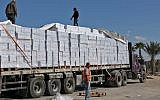 Palestinian workers inspect trucks carrying supplies after their arrival in Rafah through the Kerem Shalom crossing between Israel and the southern Gaza Strip on November 1, 2017. (AFP Photo/Said Khatib)