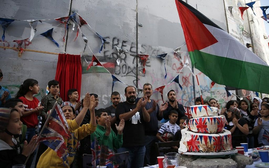 Palestinian children from the Aida refugee camp attend an event held by secretive British street artist Banksy to apologize for the 100th anniversary of the Balfour Declaration, on November 1, 2017, at his Walled-Off Hotel in Bethlehem in the West Bank. (AFP/Ahmad Gharabli)