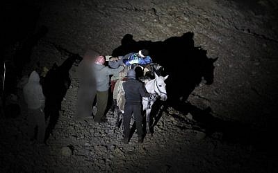 A wounded Syrian man being carried on a mule as they approach a meeting point with Israeli soldiers on Mount Hermon in the Israel Golan Heights on the border line between Israel and Syria, before being transferred to an Israeli hospital for medical treatment, October 26, 2017. Figures are blurred to prevent identification. (AFP/MENAHEM KAHANA)