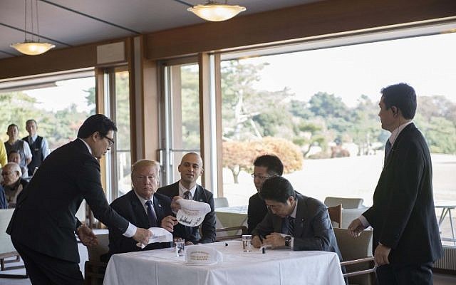 Staff members help as US President Donald Trump,left, signs hats that say "Make Alliance Even Greater" with Japanese Prime Minister Shinzo Abe, right, during a luncheon at the Kasumigaseki Country Club Golf Course in Kawagoe, Saitama prefecture, outside Tokyo on November 5, 2017. (AFP/JIM WATSON) Staff members help as US President Donald Trump,left, signs hats that say "Make Alliance Even Greater" with Japanese Prime Minister Shinzo Abe, right, during a luncheon at the Kasumigaseki Country Club Golf Course in Kawagoe, Saitama prefecture, outside Tokyo on November 5, 2017. (AFP/JIM WATSON)