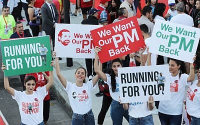Supporters of Lebanon's Prime Minister Saad Hariri hold up posters demanding his return from Saudi Arabia, on the starting line of Beirut's annual marathon, on November 12, 2017. (AFP Photo/Anwar Amro)