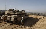 A picture taken on November 16, 2017, shows an Israeli soldier walking next to a tank at an army position overlooking southern Lebanon in the northern Israeli town of Metula, along Israel's border with Lebanon. (AFP PHOTO / MENAHEM KAHANA)